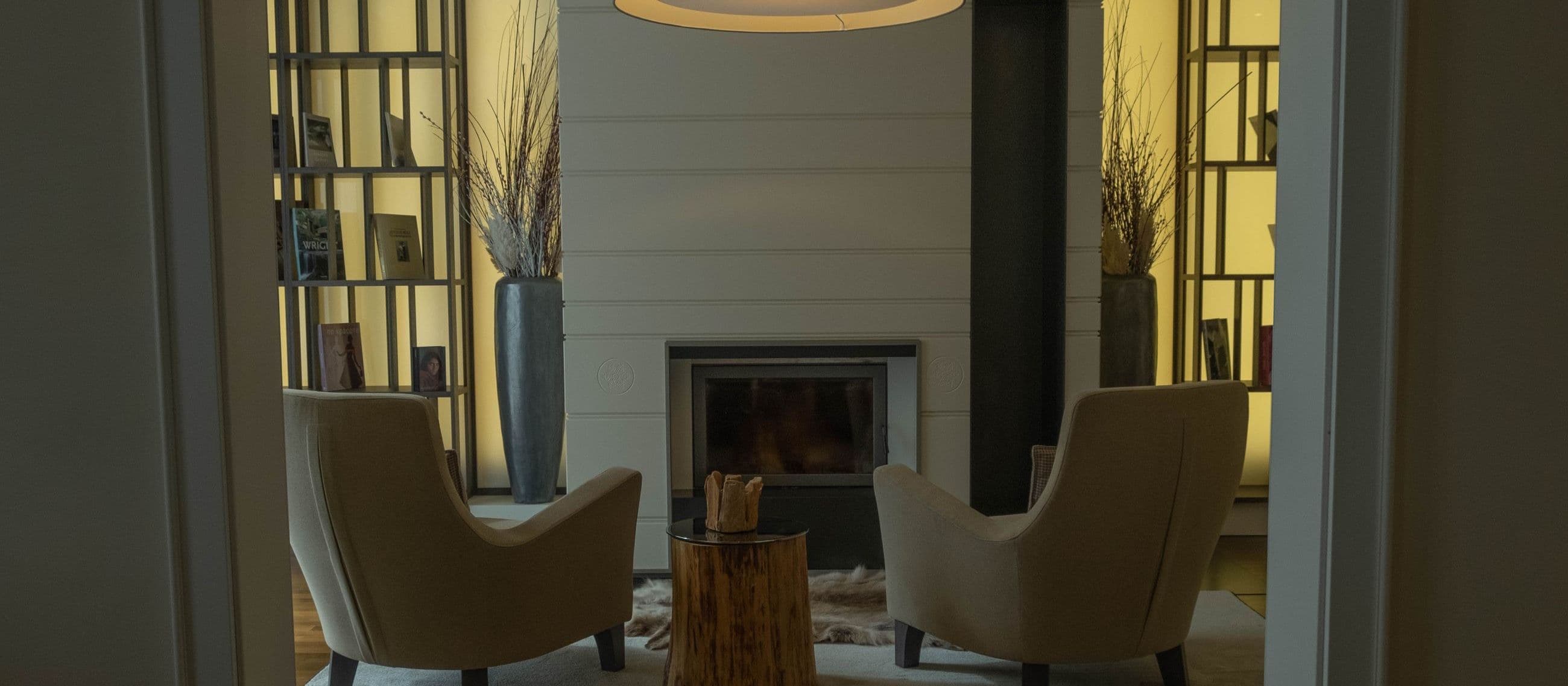 Two armchairs facing each other beside a lit fireplace in a warm, softly lit room